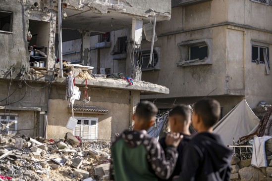 Ragazzi palestinesi davanti a un edificio residenziale distrutto da un raid israeliano a Deir al-Balah foto Ap/Abdel Kareem Hana