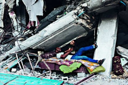 Un palestinese gioca con il suo bambino sotto le macerie della loro casa distrutta a Khan Younis foto Ap