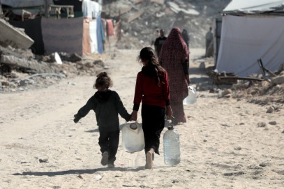 Bambini palestinesi trasportano taniche d’acqua verso la loro tenda a Khan Younis